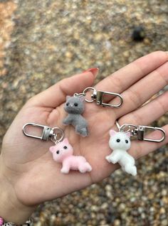 a person is holding some tiny stuffed animals in their hand and they are wearing key chains