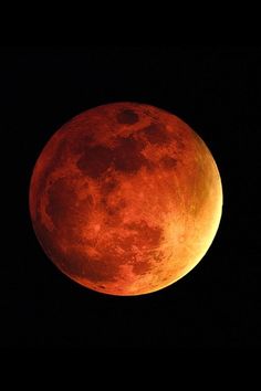 an orange moon is seen in the dark sky