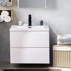 a white bathroom vanity sitting next to a mirror and towel dispenser on a wall