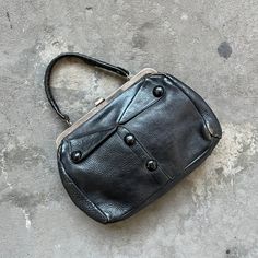 "This 1940's vintage handbag is made from a black, high quality leather and features a doctor's bag style shape with a clasp top closure and short length strap. Metal Dandy zipper closure pocket inside and wooden knot buttons detailing the outside. In excellent vintage condition with only minimal signs of wear. See below for dimensions 13\" W x 9\" H x 3-4\" W 6\" strap drop" Doctor Bag Purse Handbags, Vintage Shoulder Bag With Hasp Closure For Office, Vintage Shoulder Bag With Metal Hardware For Office, Vintage Formal Satchel With Metal Hardware, Vintage Office Shoulder Bag With Metal Hardware, Vintage Satchel With Metal Hardware For Travel, Vintage Black Shoulder Bag With Metal Hardware, Vintage Shoulder Bag With Fold Over Clasp, Vintage Black Shoulder Bag For Office