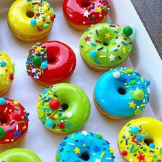 a box filled with lots of colorful donuts covered in frosting and sprinkles