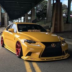 the yellow car is parked on the side of the road in front of an overpass