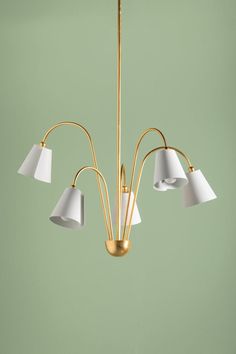 a brass chandelier with five white lamps hanging from it's center point