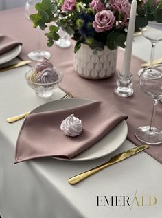 the table is set with pink flowers and gold place settings for an elegant dinner party