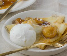 a bowl filled with bananas and ice cream on top of a white plate next to a fork