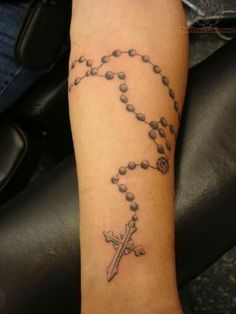 a person with a rosary tattoo on their arm