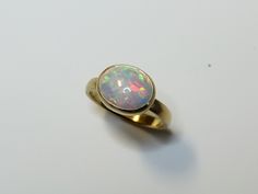 Beautiful ring made of rich 750 yellow gold with an orange red green yellow shimmering opal. A wonderful little natural spectacle! The stone is completely set in gold so that it is protected and the color is beautifully highlighted. The inside of the frame is blackened to give the play of colors more intensity. The ring band is made of oval for comfortable wearing. An absolute eye-catcher! I have more opals like this and can send you photos. Please just let us know. Dimensions Ring size: 55 or 1 Yellow Gold Ethiopian Opal Oval Cabochon Ring, Yellow Gold Ethiopian Opal Ring In Oval Cabochon Shape, Yellow Gold Ethiopian Opal Ring In Oval Shape, Ethiopian Opal Oval Cabochon Ring In Yellow Gold, Gold Ethiopian Opal Ring With Oval Cabochon, Gold Ethiopian Opal Oval Ring, Red Green Yellow, Beautiful Ring, Ring Band