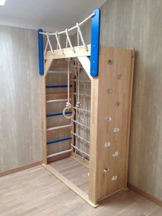 a room with a climbing wall and ladders in the middle, next to a wooden floor