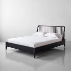 a bed with white sheets and pillows on top of it, against a gray wall