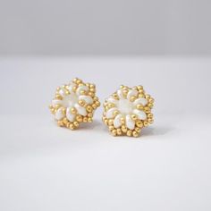 two pairs of gold and white earrings with pearls on them, one is in the shape of a flower