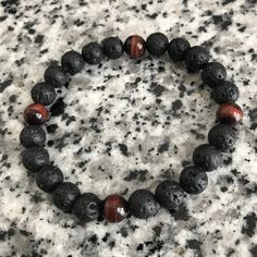 Red Tigereye And Lava Stone 8mm Beaded Bracelet A bracelet thats designed to embody strength and power. Mostly composed of lava stones with four featured red tigereye beads. Can be utilized as an oil diffuser bracelet as well. Just apply a drop of your favorite oil to the lava beads and you're set! This bracelet is crafted with quality elastic stretch cord. This bracelet is also designed to fit snug on the wrist. Laced 4 times to ensure maximum strength and hold. Most bracelets are made large un Lava Stone Beaded Bracelet Jewelry, Elegant Lava Stone Beaded Bracelets, Spiritual Black Beads Lava Stone Bracelet, Casual Hand-strung Beaded Bracelets With Lava Stone, Black Hand-strung Lava Stone Beaded Bracelets, Oil Diffuser Bracelet, Lava Stone Bracelet, Black Onyx Bracelet, Black Beaded Bracelets