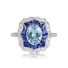 This geometric gemstone halo ring features a 0.91 carat oval-cut aquamarine. The center stone is surrounded by a halo of French-cut calibre natural sapphire, further encircled by a second halo of round brilliant diamonds. ✦ GEMSTONE SPECIFICATIONS: Gemstone: Aquamarine Gemstone Cut: Oval Cut Gemstone Weight: 0.91 Carats ✦ ENGAGEMENT RING SPECIFICATIONS: Ring Material: Platinum Stones: Aquamarine, Sapphire, Diamond ✦ WHAT COMES IN YOUR SHIPMENT: - Your Engagement Ring - Quality Ring Box - Jewelry Luxury Oval Gemstones With Halo Setting, Platinum Oval Halo Ring With Gemstone, Oval Platinum Halo Ring With Gemstone, Oval Cluster Ring With Gemstone In Platinum, Oval Platinum Cluster Ring With Gemstone, Art Deco Multi-stone Oval Sapphire Ring, Art Deco Oval Multi-stone Sapphire Ring, Oval White Gold Gemstones With Halo Setting, Art Deco Oval Sapphire Ring With Accent Stones