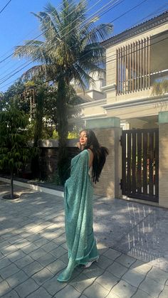 a woman is standing on the sidewalk with her hair in the air and wearing a blue towel