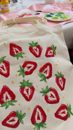 a bag with strawberries painted on it sitting on a table next to other plates and utensils