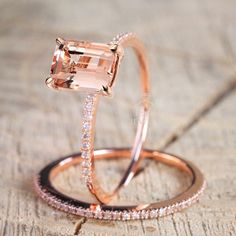 an engagement ring and wedding band are shown on a piece of wood