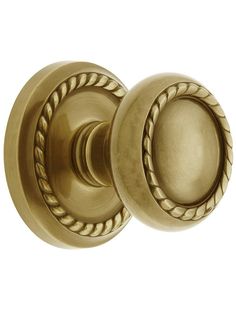 an antique brass door knob with roped design on the front and side handles, set against a white background