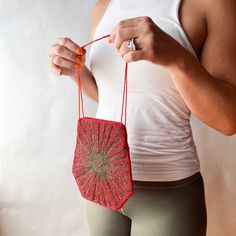 a woman is holding a red bag and string