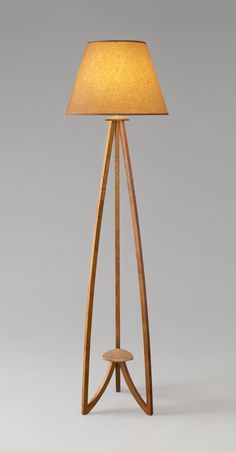 a wooden floor lamp with a beige shade on the top and bottom part of it