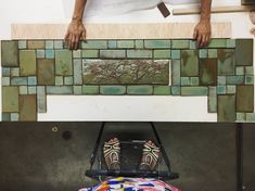 a man standing on top of a table next to a chair and tiled back splash