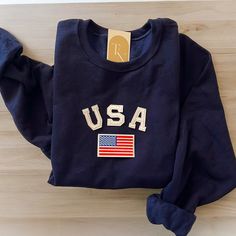 This unique and trendy USA Flag Crewneck Sweatshirt makes the perfect 4th of July outfit! This makes a perfect election sweatshirt as well!  - Our sweatshirt material is super soft and comfy! ♡ (50% cotton. 50% polyester) - These letters are iron-on patches that have been heat pressed, not embroidered. Rest assured, they'll be fully in tact! - All our sweatshirts run a UNISEX fit. (Both for men and women) They are naturally oversized, so we normally recommend your true size. But if you like a mo Fall Flag Print Crew Neck Sweater, Long Sleeve Flag Print Sweater For Fall, Fall Flag Print Long Sleeve Sweater, Fall Long Sleeve Flag Print Sweater, Casual American Flag Sweater For 4th Of July, Casual Crew Neck Sweater With American Flag Print, Long Sleeve Cotton Tops For 4th Of July, Cotton Long Sleeve Top For 4th Of July, Navy Cotton Collegiate Sweatshirt