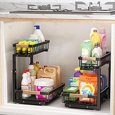 two black baskets filled with cleaning supplies on top of a kitchen sink under a faucet