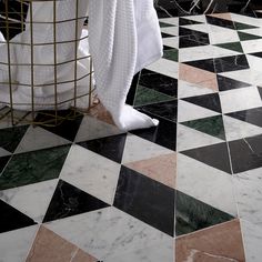 a bathroom with black, white and green marble flooring next to a shower curtain