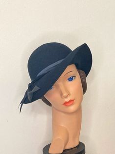 Vintage hat reproduction in Marlene Dietrich style.  Inspired by the very feminine and at the same time sporty fashion of the 1930s, this simple hat describes the typical line of the hats of that time with its delicate crown and the cleverly curved brim, which women can also wear with day dresses and of course with Slacks.  A real eye-catcher for the stylish 30s look during the day.  Material: Hat 100% wool  Lining band 98% cotton 2% elastane  Grosgrain trimmings: 100% cotton  Satin band: 100% s Fitted Cloche Hat With Curved Brim, Classic Navy Wide Brim Hat, Fitted Navy Wide Brim Hat, Navy Fitted Wide Brim Hat, Navy Fitted Hat With Short Brim, Navy Curved Brim Formal Hat, Navy Formal Hat With Curved Brim, Marlene Dietrich Style, Marlene Dietrich