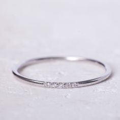 a white gold ring with three diamonds on it, sitting on top of a table