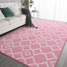 a living room with a white couch and pink rug on the floor in front of a window