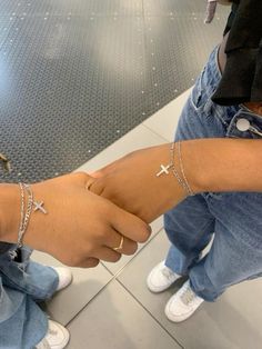 two people wearing cross bracelets on their arm with one holding the other's hand