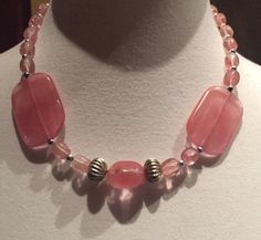 I would consider this 16"  pink necklace a choker since it hangs by the neck. The two large flat beads make a nice contrast to the other smaller beads. The perfect necklace to brighten your day. No maker is on this piece. In very good vintage condition. These beads look like stone but I'm pretty sure they are plastic of some sort. The shipping weight will be 4 ounces. Pink Handmade Choker With Round Beads, Handmade Pink Choker With Round Beads, Adjustable Pink Necklace With Gemstone Beads, Adjustable Pink Gemstone Beads Necklace, Pink Necklaces With Polished Beads For Gifts, Pink Polished Beaded Necklaces For Gifts, Pink Necklace With Polished Beads For Gift, Pink Polished Bead Necklace For Gift, Adjustable Pink Necklace With Large Beads