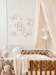 a baby crib in a white room with butterflies on the wall and teddy bear next to it