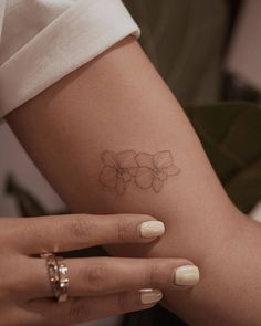 a woman's arm with a small flower tattoo on the left side of her arm