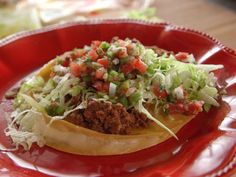 a taco filled with meat, lettuce and tomatoes on a red plate