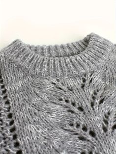 a close up of a sweater with holes in it on a white surface, showing the stitchs