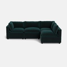 a green sectional sofa with pillows on the top and bottom, in front of a white background