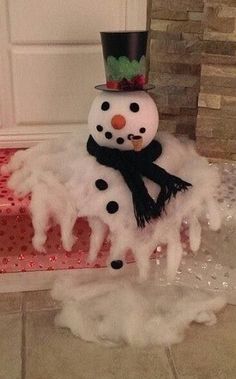 a snowman with a top hat and scarf on it's head sitting in front of a door