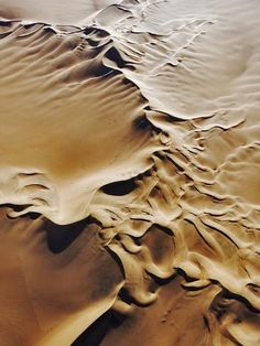 an aerial view of sand dunes in the desert, with ripples and patterns on them