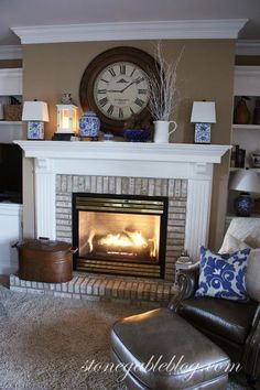 a living room with a fire place and a clock on the wall above it's mantle