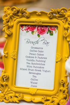 a yellow framed sign with flowers on it sitting next to a cup and saucer