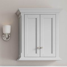 a white bathroom wall mounted cabinet next to a light