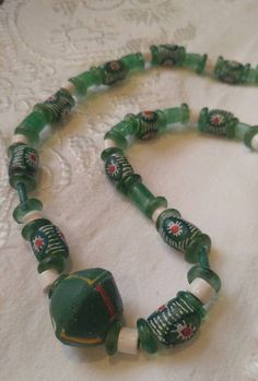 Hand-painted jade green clay and glass beaded necklace is sure to add a global chic vibe to your outfit.  A one-of-a-kind accessory that is curated from my large collection of vintage and hand-crafted beads.  At 13 inches long it will easily slip over your head. As with all my necklaces, it is finished with a tassel and a charm to remind you that it was made with love.  Enjoy! Bohemian Single Strand Jade Beaded Necklace, Artisan Green Jewelry With Wooden Beads, Vintage Jade Beaded Necklace, Green Bohemian Jewelry With Wooden Beads, Traditional Handmade Jade Beaded Necklaces, Traditional Green Jade Necklaces, Green Bohemian Single Strand Jewelry, Bohemian Green Single Strand Jewelry, Handmade Green Glass Necklaces