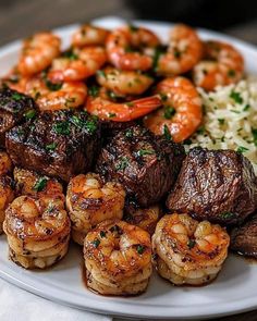 a white plate topped with steak and shrimp next to rice covered in garnish