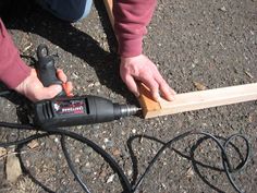 a person using a power drill to attach a piece of wood on top of the ground