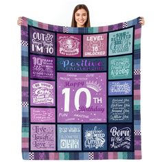 a woman is holding up a quilt that has the words and numbers on it in different colors