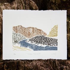 a piece of paper sitting on top of a tree trunk with mountains in the background