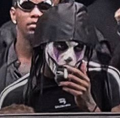 a man with his face painted as the joker is holding a cell phone in front of him