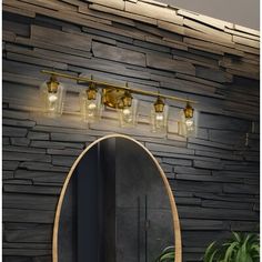 a bathroom with a round mirror and lights on the wall next to a potted plant