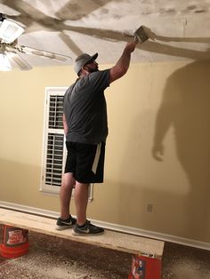 a man is painting the ceiling in his living room with paint rollers on it