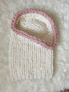 a white and pink crocheted bag laying on top of a rug